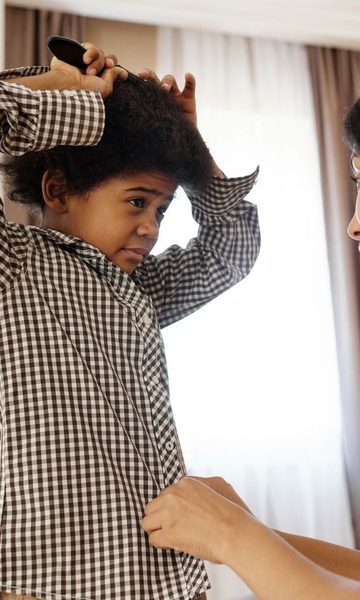 A mother helping her son put on his shirt